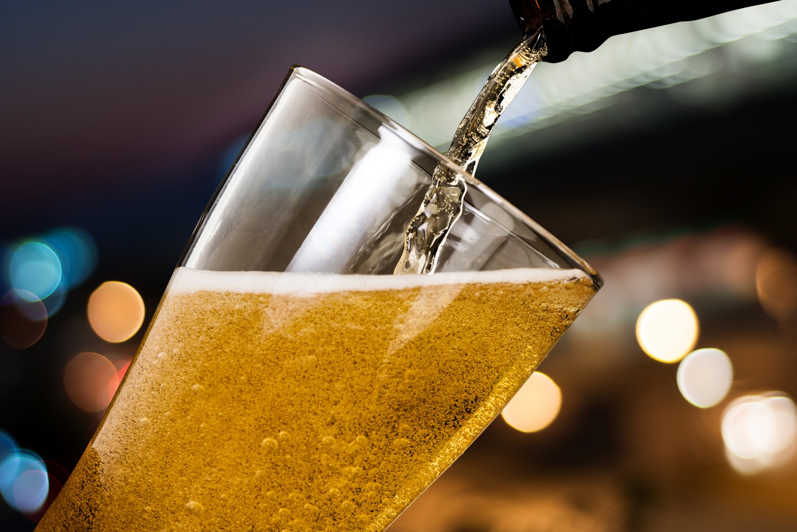 Motion Of Beer Pouring From Bottle Into Glass On Bokeh Light Night Background